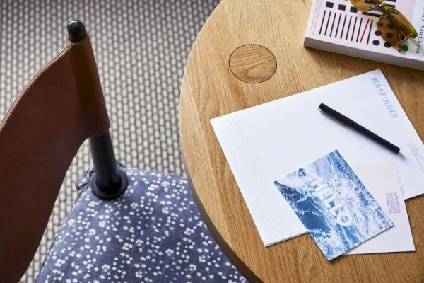 A round wooden table with a pen, a postcard that says 