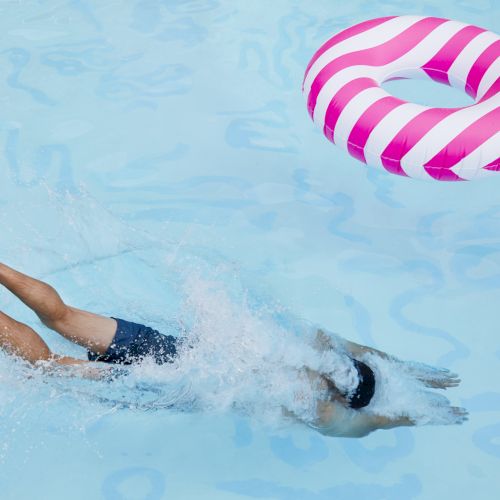 Two flip-flops floating on clear water, joined by a string, with a small pink-and-white striped pattern on one.