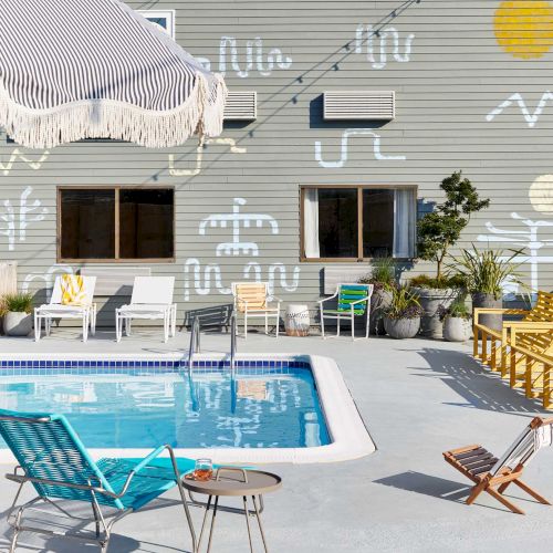 A sunny backyard with a modern two-story house, a shaded patio, a swimming pool, lounge chairs, and a bright, inviting outdoor setup.