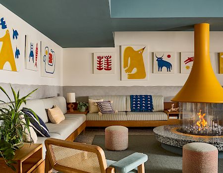 Bright modern living room with a sofa, fireplace, yellow floor lamp, and framed animal artwork on white walls.