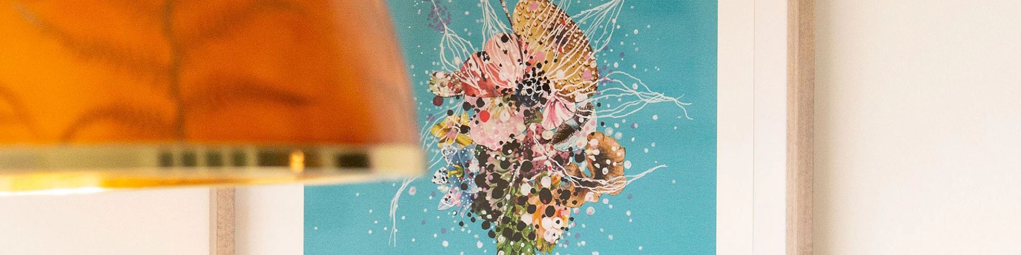 The image shows an abstract floral painting with vibrant colors on a blue background, partially obscured by an orange lampshade.