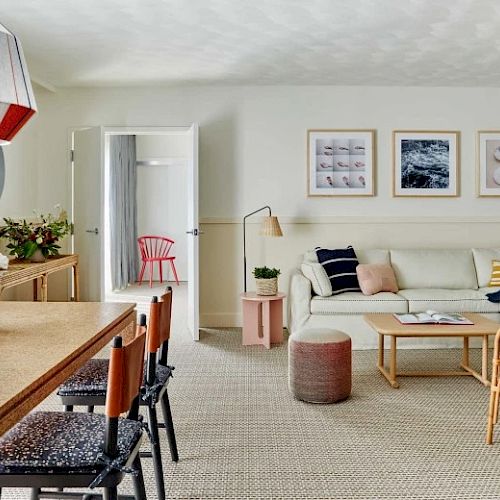 The image showcases a modern living room with a dining area, featuring stylish decor, wooden furniture, and framed art on the walls.