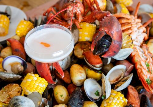 Seafood boil with lobster, shrimp, mussels, clams, corn and potatoes, with a bowl of melted butter sauce.
