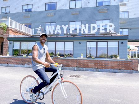 A person rides a bicycle in front of a building with a sign reading 