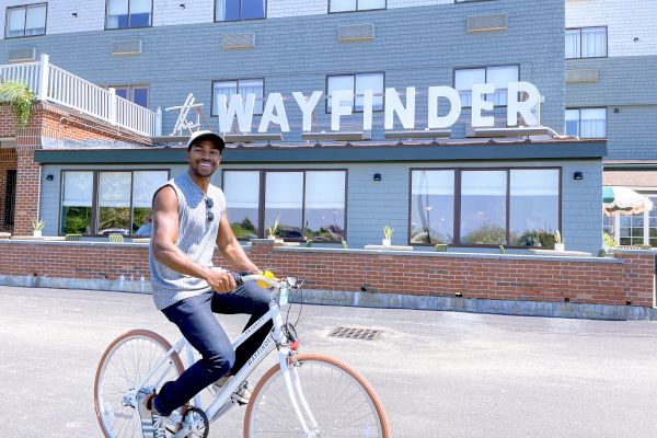 A person rides a bicycle in front of a building with a sign reading 