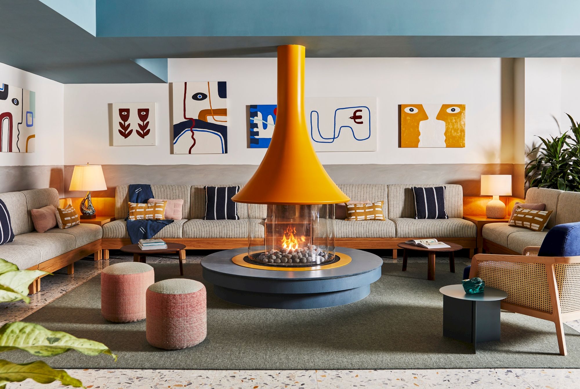 A stylish living room with a central orange fireplace, abstract wall art, cozy seating, and warm lighting completes the modern aesthetic.